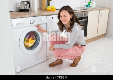 Young Happy Woman Cleaning Multi-colored Clothes In Washing Machine At Home Stock Photo