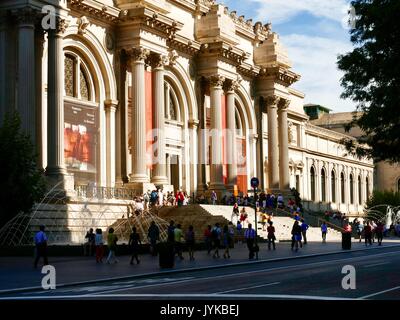 Crowds gather outside on the steps of The Metropolitan Museum of Art - The Met - as buildings opposite cast early morning shadows. New York, NY, USA. Stock Photo