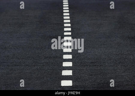 New white intermittent road markings on black asphalt. Stock Photo