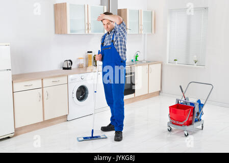 Young Male Worker Cleaning Floor With Mop In House Stock Photo