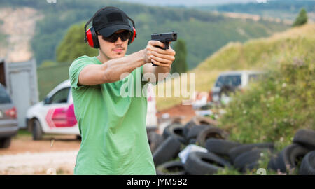 Handsome young guy wants to shoot enemy target in the wilderness with all professional army police special forces equipment gear killing bullets and t Stock Photo