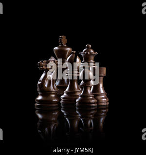 Creative business concept photo of black wooden chess figures standing together as a family ready for game against dark background. Stock Photo
