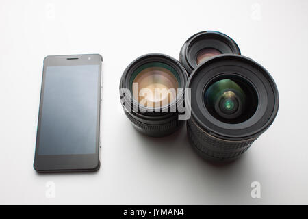 close-up of group of camera lenses and a mobile phone on a white background Stock Photo