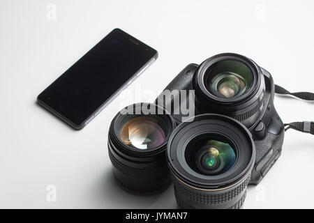 close-up of group of camera lenses and a mobile phone on a white background Stock Photo