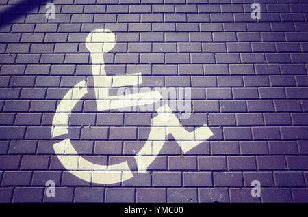 Vintage toned picture of the International Symbol of Access (ISA) painted on a street. Stock Photo
