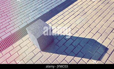 Vintage toned picture of a concrete block on pavement, abstract urban background. Stock Photo