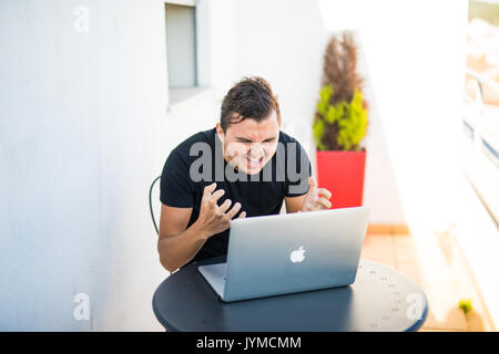 Young man working on laptop with outdoors view. Stock Photo