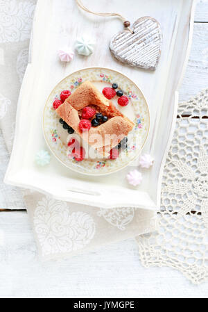 Apple pie decorated with raspberries and blueberries, french macaroons around. Birthday party table. Stock Photo