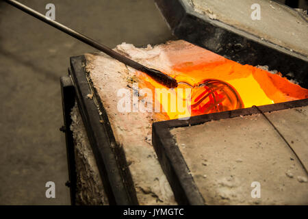 Handmade figure of melted glass, a glass blower working molten glass on a rod Stock Photo