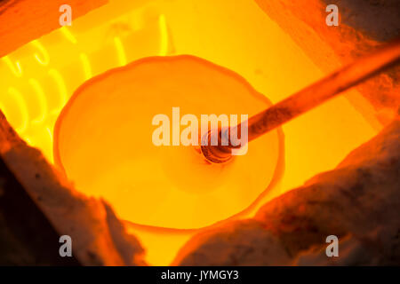 Handmade figure of melted glass, a glass blower working molten glass on a rod Stock Photo