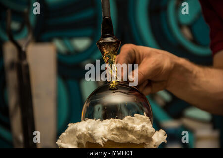 Handmade figure of melted glass, a glass blower working molten glass on a rod Stock Photo