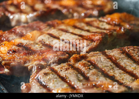 Raw Ribeye Steak with Herbs and Spices, frying on grill pan. Stock Photo