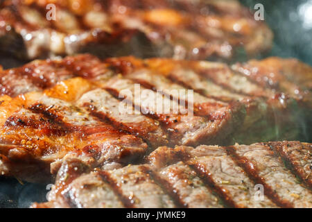 Raw Ribeye Steak with Herbs and Spices, frying on grill pan. Stock Photo