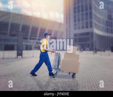 Male courier with trolley in city. Distribution business. Cargo delivery. Empty, clear containers. Logistic and post service Stock Photo