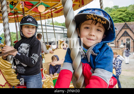 A couple of young brothers have fun riding on a merry go round. Stock Photo