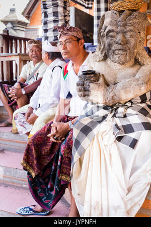 Traditional costume for men and statue at a Royal Cremation ceremony in Ubud, Bali, Indonesia Stock Photo