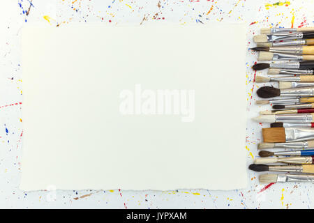 various paintbrushes set and blank white sheet of paper on background with watercolor blobs Stock Photo