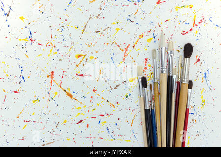 various sizes of paintbrushes on white paper with watercolor blobs background Stock Photo