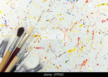 different artist paintbrushes and paints on background of watercolor splashes Stock Photo