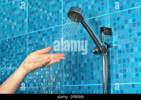 Close-up of a woman's hand check water temperature in the shower with hand shower wall. Stock Photo