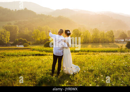 Couple enjoying romantic sunset view in the field Stock Photo