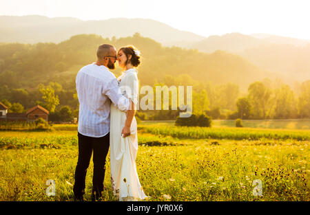 Couple kissing during a romantic sunset in the field Stock Photo