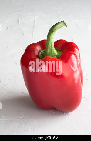 Red bell pepper isolated on stucco textured white surface with space for text - Vertical image  Paprika pepper background Stock Photo