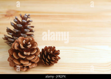 Three natural dry pine cones isolated on light brown wooden table, with free space for text and design Stock Photo
