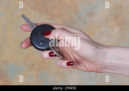 Female hand holding car key pressing remote control unlock button Stock Photo