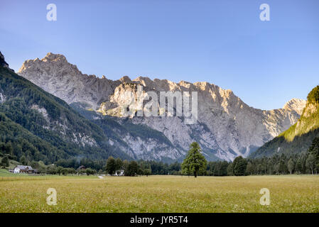 Logarska dolina - Logar valley, Slovenia in sunrise, mountain peaks brightly lit by golden colors of the sun. A popular tourist and travel destination Stock Photo
