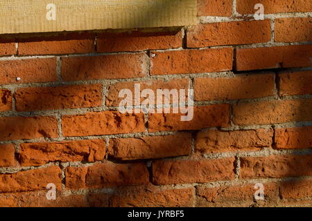Nineteenth century brick wall with shadow and limestone frame to left Stock Photo