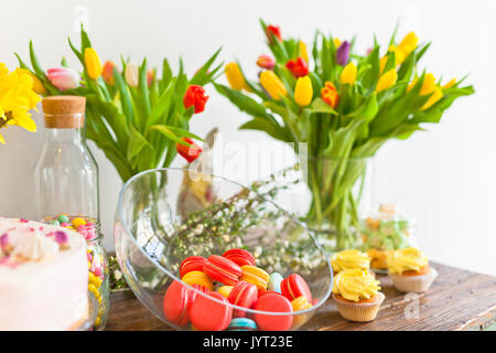 Bright macaroons and cupcakes on a wooden table. Indoors natural light shot with small depth of field Stock Photo