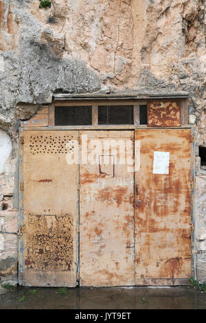 Old rusty door in weathered rock Stock Photo