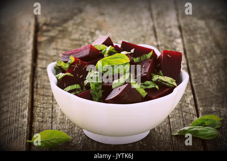 Beetroot chopped for salad with basil and dill seeds in bowl on rustic wooden table Stock Photo