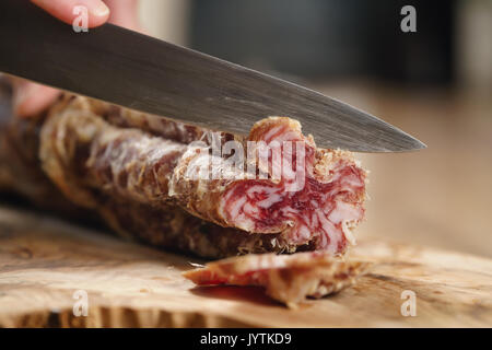 closeup shot of slicing salami with knife Stock Photo