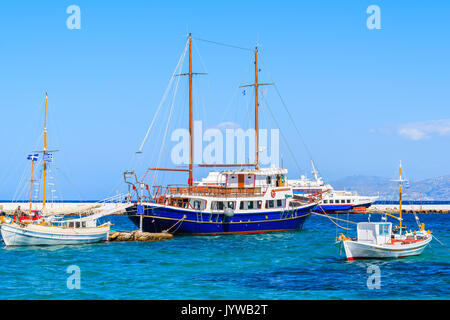 MYKONOS PORT, GREECE - MAY 17, 2016:Sailing and fishing boats on blue sea in Mykonos port, Mykonos island, Greece. Stock Photo