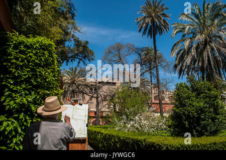 Spain: painter with canvas and tripod in the Gardens of Charles V in the Alcazar of Seville, the famous royal palace, example of mudejar architecture Stock Photo