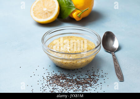 lemon curd chia pudding in a glass bowl,, fresh lemons on a blue background Stock Photo