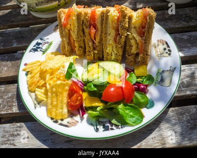 Lunchtime snack on an outside table cheese and tomato sandwich with salad and potato crisps North Yorkshire England Stock Photo