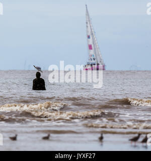 Liverpool, UK. 20th Aug, 2017. Liverpool 2018 Clipper boat passes a watching Iron Man captured from Crosby beach.  The Clipper Race (now in its eleventh year) sees twelve global teams compete in a 40000 nautical mile around the world race on a 70 foot ocean racing yachts.  The teams left the host port of Liverpool on 20 August 2017 to begin their first leg – a 5200 mile mile journey lasting approximately 33 days to South America, taking in the Canary Islands & Doldrums along the way. Credit: Jason Wells/Alamy Live News Stock Photo