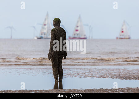 Liverpool, UK. 20th Aug, 2017. An Iron Man watches the start of the 2017/18 round the world Clipper race on a beach near Liverpool.  The Clipper Race (now in its eleventh year) sees twelve global teams compete in a 40000 nautical mile around the world race on a 70 foot ocean racing yachts.  The teams left the host port of Liverpool on 20 August 2017 to begin their first leg – a 5200 mile mile journey lasting approximately 33 days to South America, taking in the Canary Islands & Doldrums along the way. Credit: Jason Wells/Alamy Live News Stock Photo