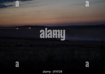 Night harvest, harvesters are reaping on a wheat field. Stock Photo