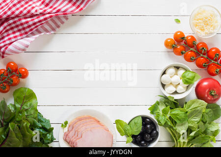 Fresh food ingredients for italian cuisine. Bunch of green basil, black olives, mozzarella cheese, ham, grated parmigiano, swiss chard and tomatoes on Stock Photo