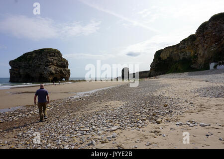 People on the beach at Marsden Rock a Rocky Formation of Limestone  off the North Sea Coast in South Shields England Stock Photo