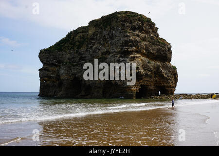 People on the beach at Marsden Rock a Rocky Formation of Limestone  off the North Sea Coast in South Shields England Stock Photo