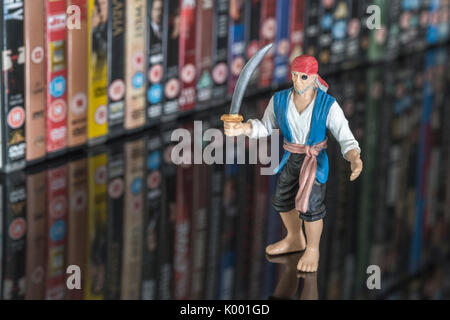 Sword wielding toy pirate standing in front of stacks of DVDs (Digital Versatile Disc) - metaphor software piracy, Chinese counterfeit goods, IP theft Stock Photo
