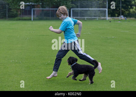 young boy running with dog Stock Photo