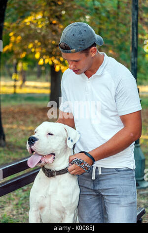 Teenage boy with his dog - Dogo Argentino in the park Stock Photo
