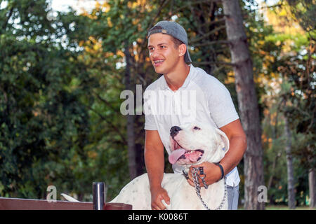Teenager boy walks with his dog in the park - Dogo Argentino Stock Photo