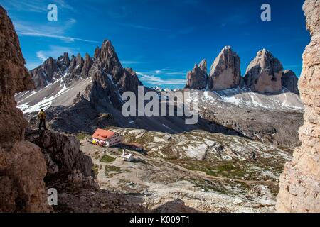 Hiker enjoying the view of the Sesto Dolomites with Locatelli refuge, the three peaks of Lavaredo and Mount Paterno in the background. Locatelli refug Stock Photo